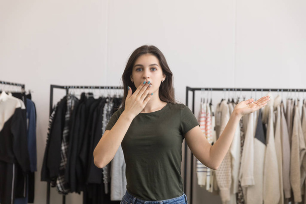 Young girl in a clothing store covers her mouth with her hand. - Foto, immagini