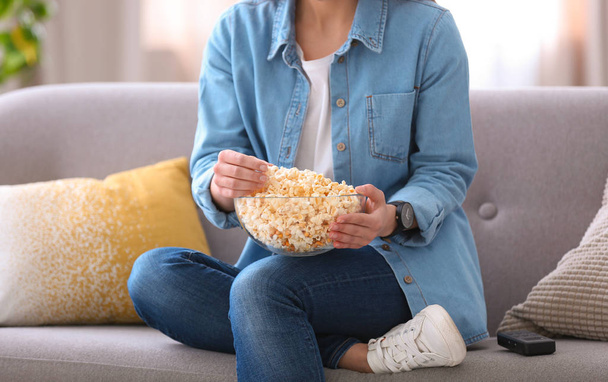 Young woman watching movie with popcorn in living room, closeup - Foto, Bild