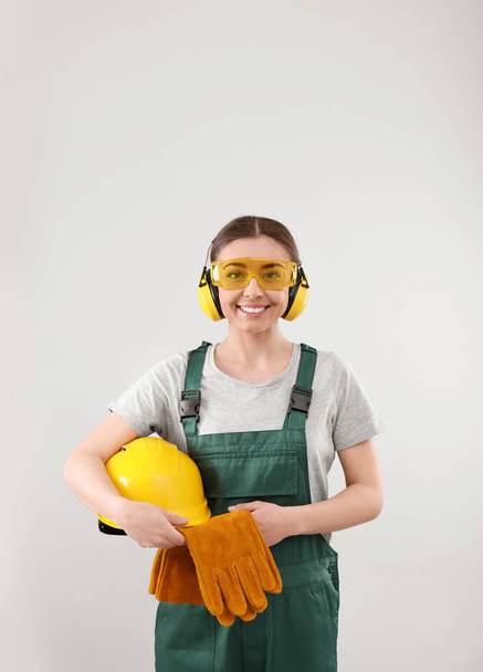 Female industrial worker in uniform on light background. Safety equipment - Foto, Imagen