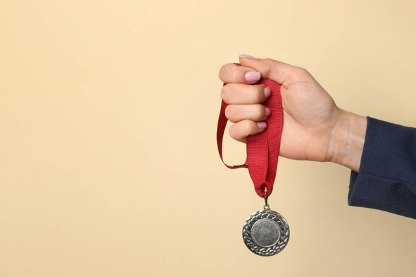 Woman holding golden medal on color background, closeup. Space for text - Foto, Bild