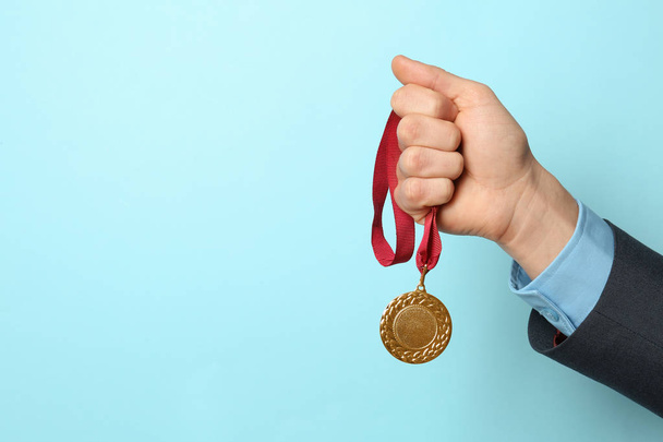 Man holding golden medal on color background, closeup. Space for text - Фото, зображення