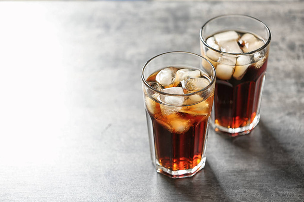 Glasses of cola with ice on grey background, space for text - Fotó, kép
