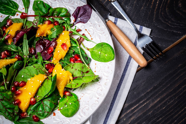 L'insalata biologica con mango, melograno, lattuga e rucola su piatto bianco. Cibo piatto laici. Vista dall'alto - Foto, immagini