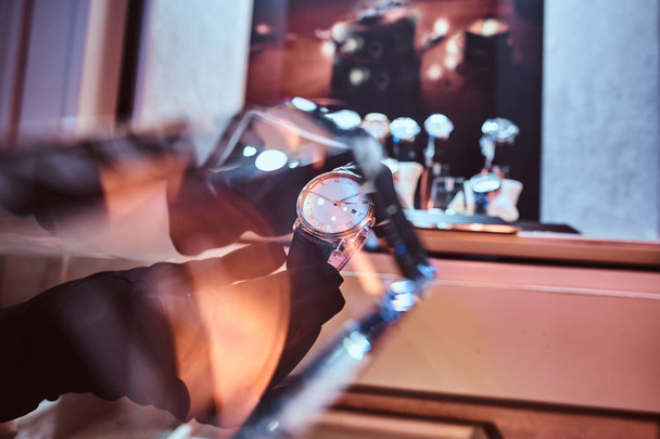 Γκρο πλαν των πωλητών χέρια γάντια δείχνει την αποκλειστική mens ρολόι από τη νέα συλλογή - Φωτογραφία, εικόνα