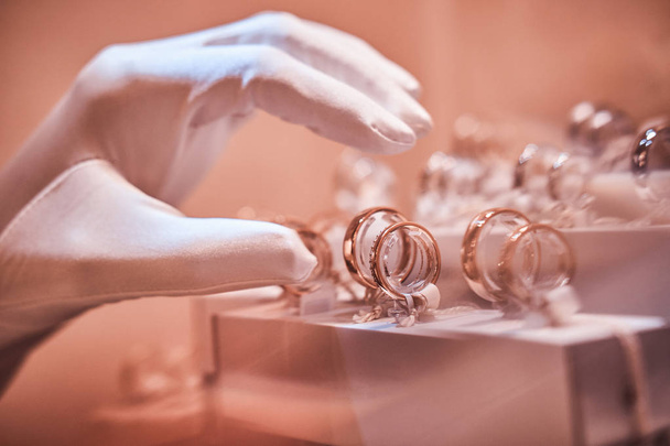 Hand in gloves takes to exclusive rings on the showcase of a jewelry store - Φωτογραφία, εικόνα