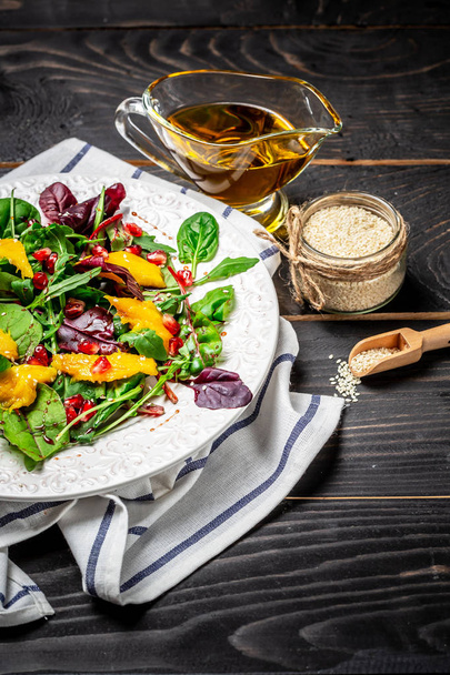 Frischer Salat mit Mango, Granatapfel, Salat und Rucola auf weißem Teller. Veganer Salat. Ernährungsmenü. Ansicht von oben - Foto, Bild