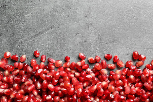 Pomegranate seeds on grey background, top view with space for text - Foto, afbeelding