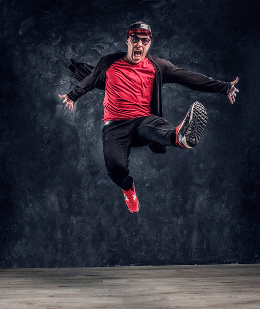 Emotional stilvoll gekleideter Typ, der Breakdance-Springen aufführt. - Foto, Bild