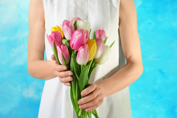 Girl holding bouquet of beautiful spring tulips on color background, closeup. International Women's Day - Foto, Imagem