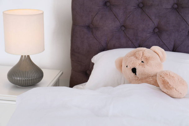Cute teddy bear lying in bed indoors. Space for text - Fotó, kép