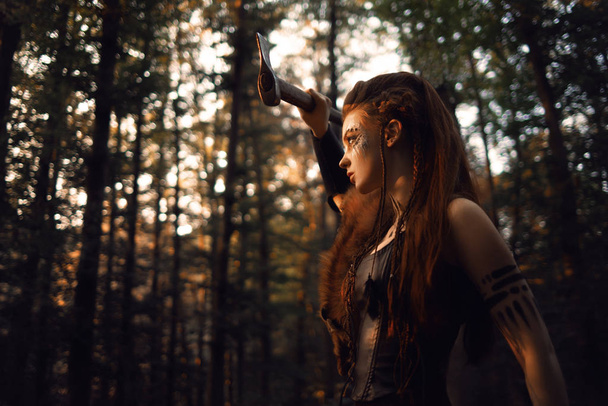attractive female hunter with tribal makeup posing in forest  - Fotografie, Obrázek