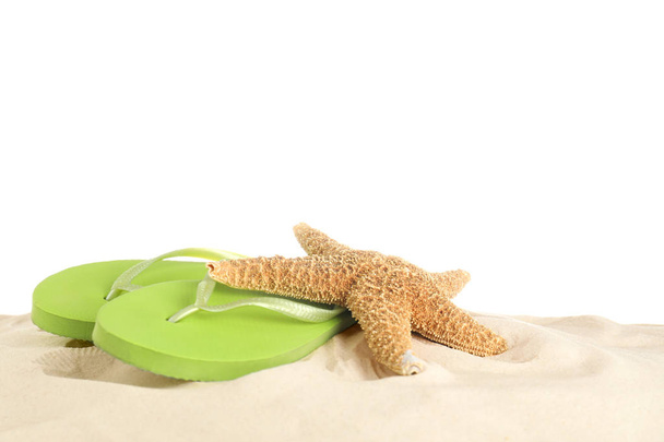 Klapki i rozgwiazdy na piasku na białym tle. Akcesoria plażowe - Zdjęcie, obraz