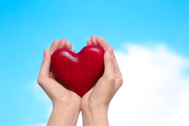 Woman holding decorative heart in hands on color background, space for text - Fotografie, Obrázek