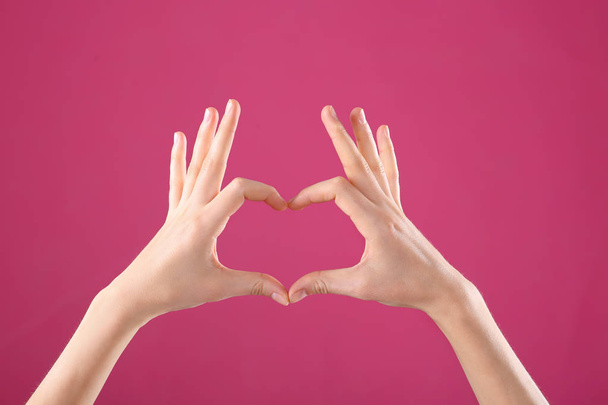 Woman making heart with her hands on color background, closeup - Fotoğraf, Görsel