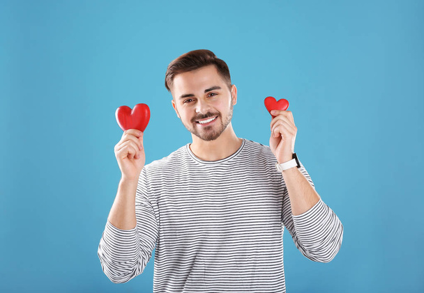 Man holding decorative hearts on color background - 写真・画像