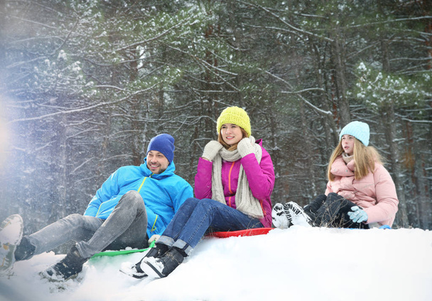 Happy family sledding in forest on snow day - Photo, Image
