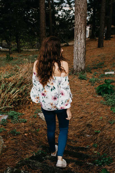 young woman with curly hair walking through the woods - Photo, image