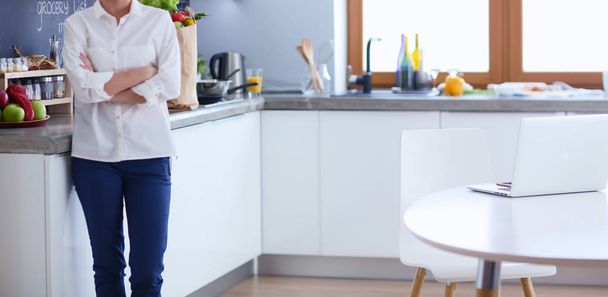 Portrait of young woman standing with arms crossed against kitchen background. Woman in the kitchen. - Foto, Bild