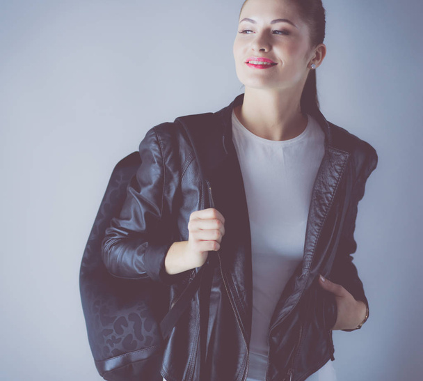 portrait of beautiful young brunette woman in stylish black jacket on gray. - Foto, afbeelding