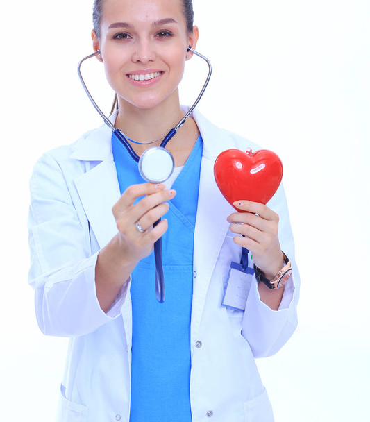 Positive female doctor standing with stethoscope and red heart symbol isolated. Woman doctor - Foto, Imagen