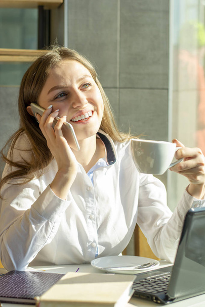 piękna dziewczyna kobieta interesu w kawiarni rozmawia przez telefon i picia kawy - Zdjęcie, obraz