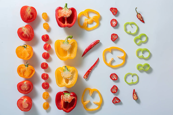 Plat lag samenstelling met tomaten en paprika's op witte achtergrond - Foto, afbeelding