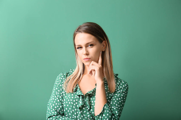 Suspicious young woman on color background - Photo, Image