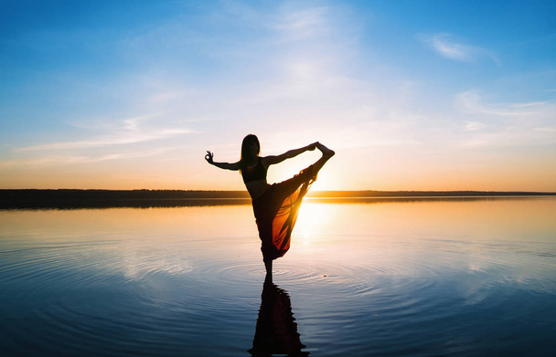 Silhouet yoga vrouw op het strand bij zonsondergang. - Foto, afbeelding