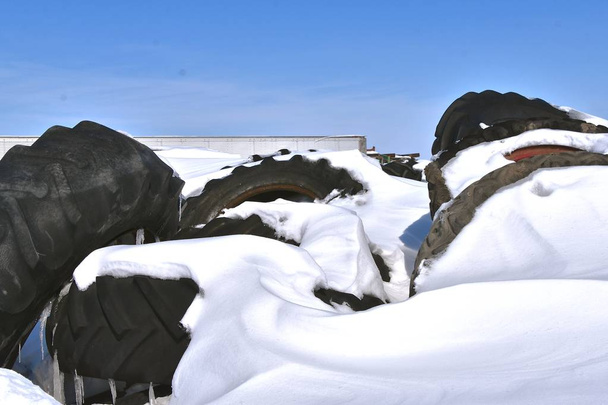 Pilhas de enormes pneus tratores são parcialmente enterrados depois de uma nevasca deixa volumes de neve
. - Foto, Imagem