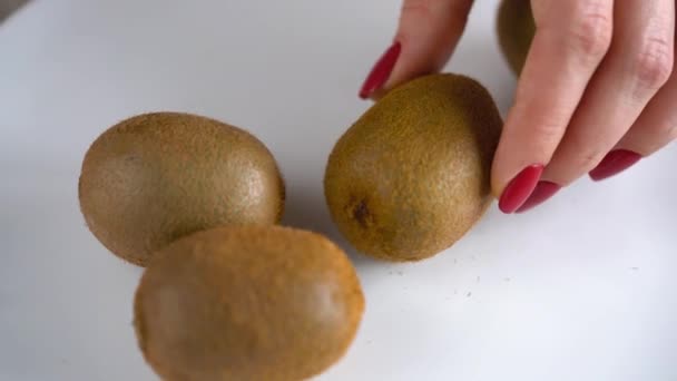 Female hands cut the kiwi with a knife, close up - Filmati, video