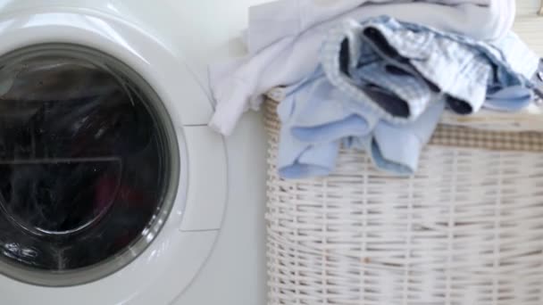 Wasserij wordt gewassen in de wasmachine, en schone dingen zijn op de mand in de buurt. - Video