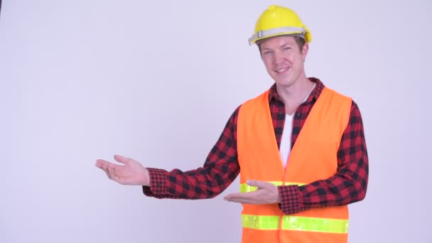 Happy young man construction worker showing something - Filmagem, Vídeo