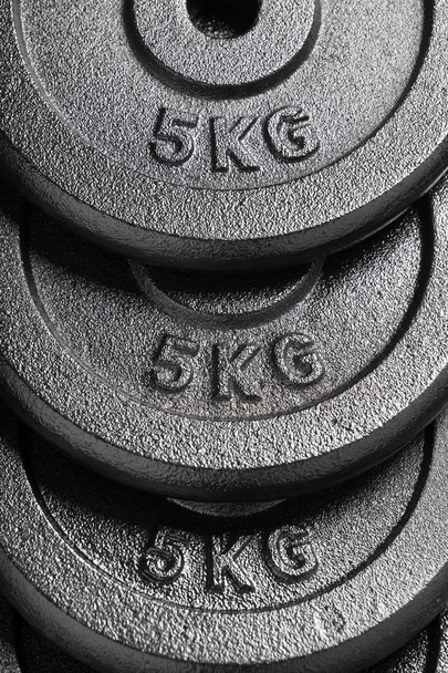 Pila de placas de peso de barra / mancuerna de 5 kg dentro de un gimnasio de levantamiento de pesas
 - Foto, Imagen
