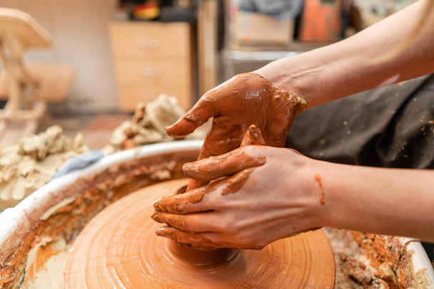 Dokonywanie ceramiki misa ręce rzemieślnika. Kobieta pracuje nad potter koła. Rodzinna firma sklep rzeźbi garnek z gliny widokiem na góry. - Zdjęcie, obraz