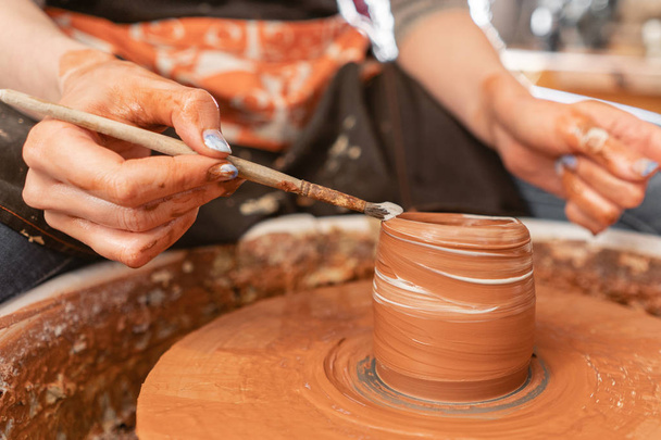 Руки майстра роблять керамічну чашу. Жінка працює на гончарному колесі. Сімейний бізнес магазин скульптури горщик з глини вид зверху
. - Фото, зображення