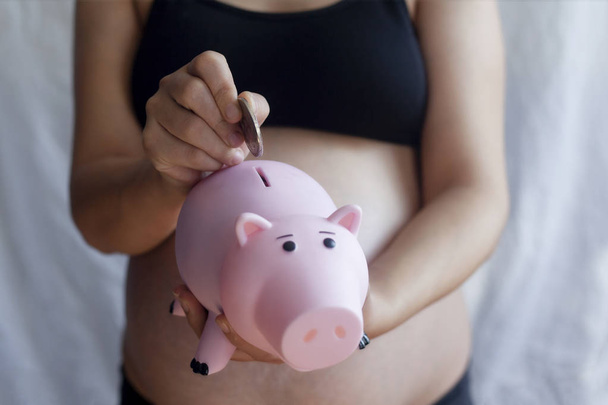 Pregnant Woman Putting Money Into Piggy Bank - Photo, Image