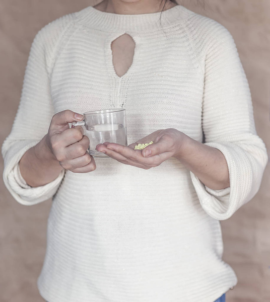 Αυτοκτονία ή έκτρωση έννοια. Μια γυναίκα που κρατάει πολλά χάπια και ένα ποτήρι νερό - Φωτογραφία, εικόνα