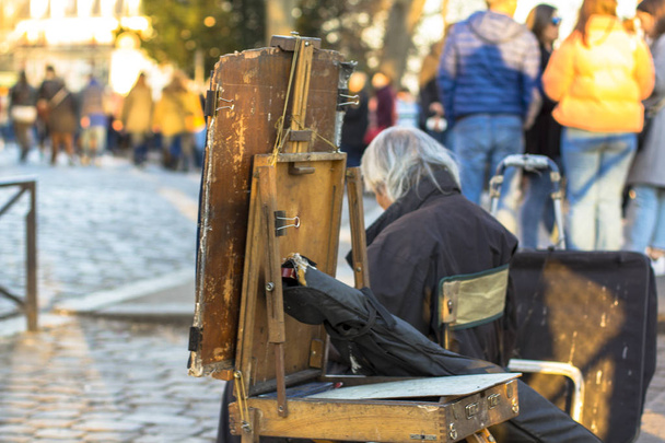 Easel y canoso artista callejero sentado y triste en la calle
 - Foto, imagen