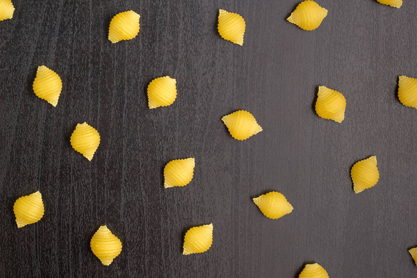 Patroon van een stapel Conchiglie-pasta schelpen op een zwarte achtergrond - Foto, afbeelding