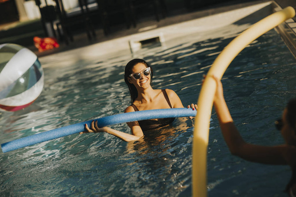 Молодые женщины веселятся с лапшой бассейна в жаркий летний день
 - Фото, изображение