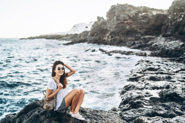 Pretty long hair tourist girl relaxing on the stones near sea. - Fotografie, Obrázek