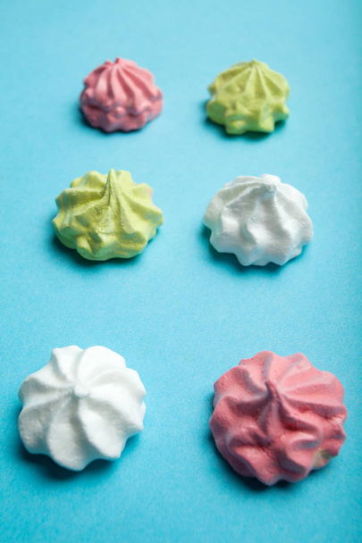 Sweet delicate meringue cakes on a blue background, the concept  - Fotó, kép
