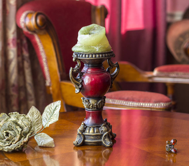 Vintage kandelaar op de tafel naast een kunstmatige rose en een haarspeld in het idee van een vlinder. Klassiek interieur. - Foto, afbeelding