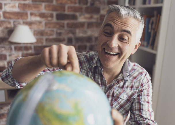 Man holding a globe and finding locations - Valokuva, kuva
