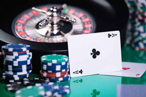  casino background, poker chips and cards on gaming table, roulette wheel in motion - Photo, Image