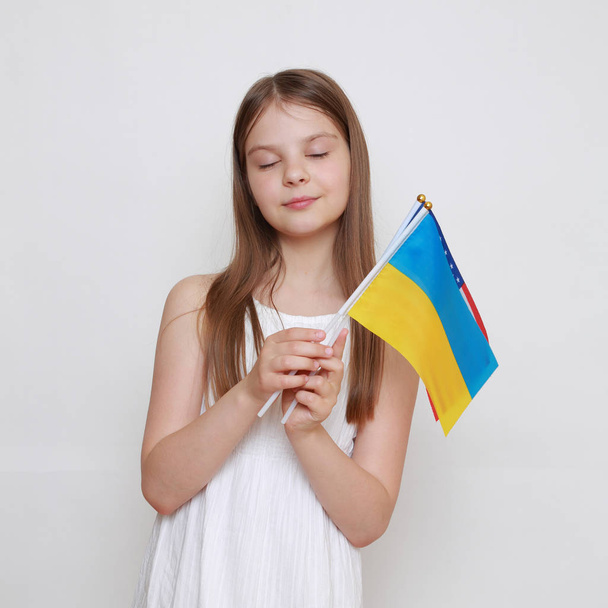 little girl holding Ukrainian and American flags - 写真・画像
