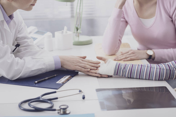 Pediatrician examining a young girl with an injured wrist - Valokuva, kuva