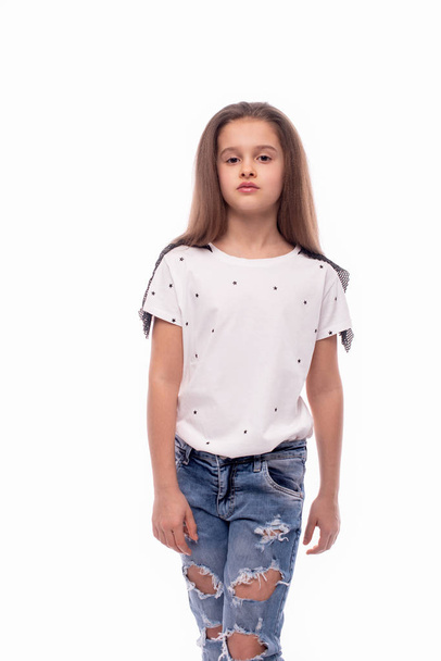 Студійний знімок маленької серйозної дівчинки в джинсах і білому блі
 - Фото, зображення
