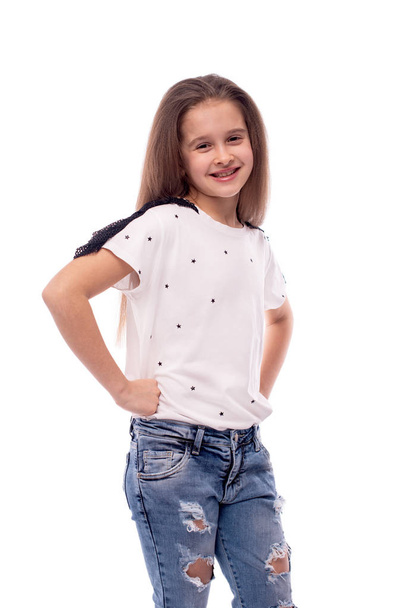 Foto de estudio de una niña sonriente con pantalones vaqueros y blanco bl
 - Foto, imagen