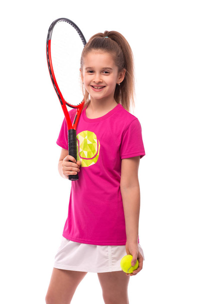 Φωτογραφία από ένα μικρό χαμογελαστή κορίτσι ντυμένο με ροζ μπλουζάκι και - Φωτογραφία, εικόνα